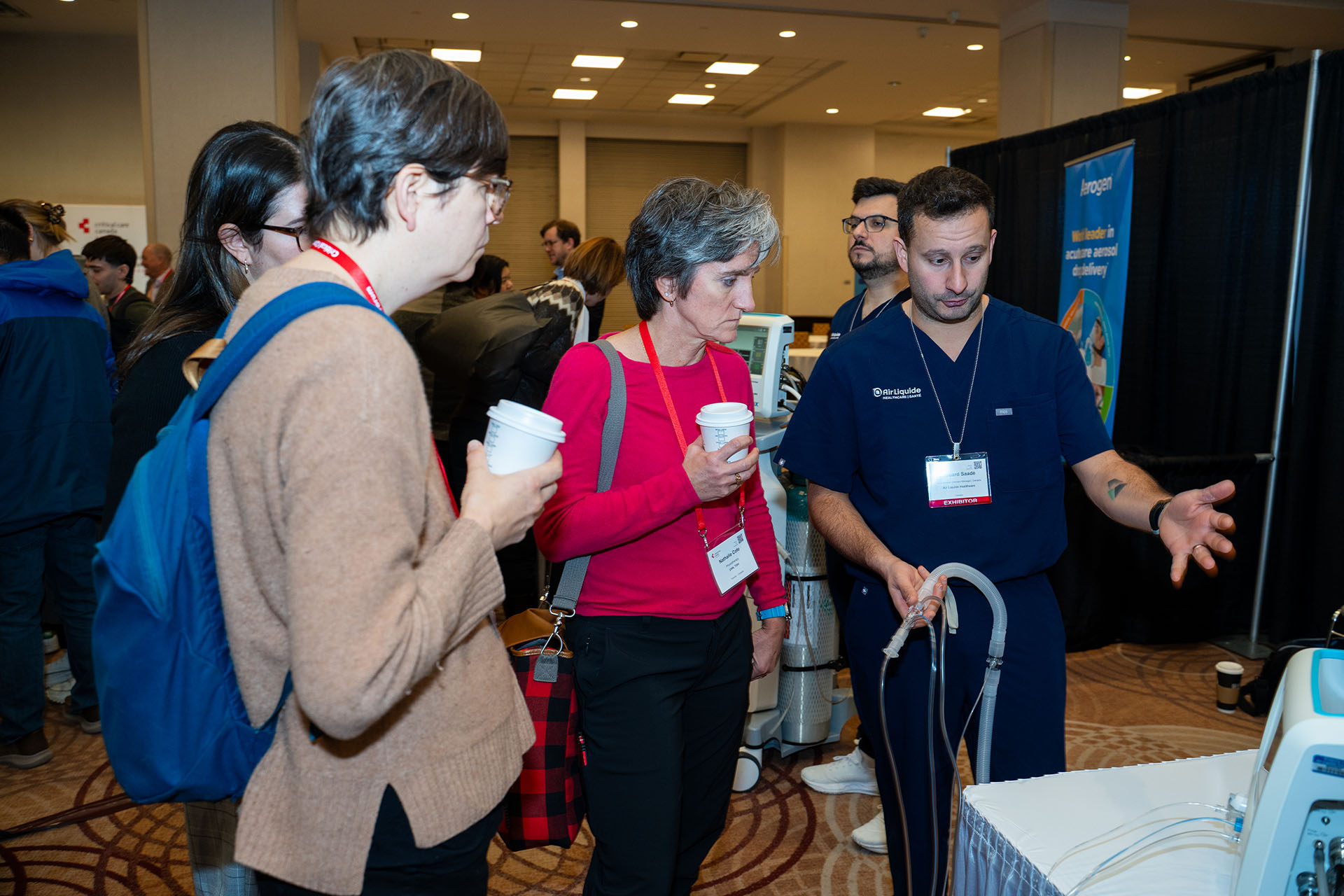 People examining medical ventilator equipment made of plastic and metal in a beige and brown conference room