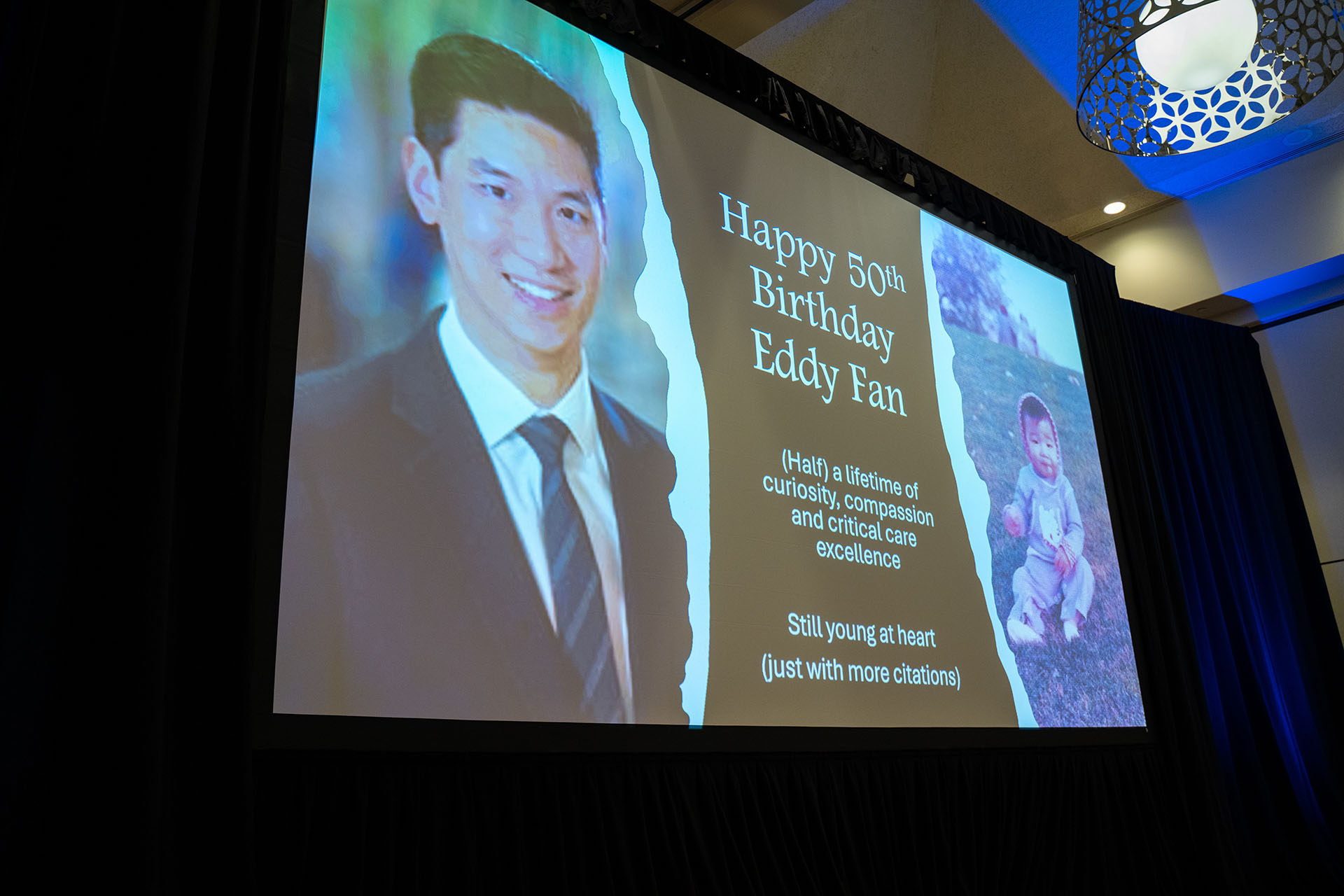 birthday presentation screen showing photos on fabric projector screen with black curtain and blue light